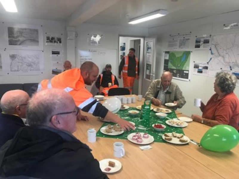 Men and women sat at table with drinks and cake