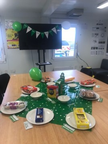 Table set out with green table cloth with plates of cake