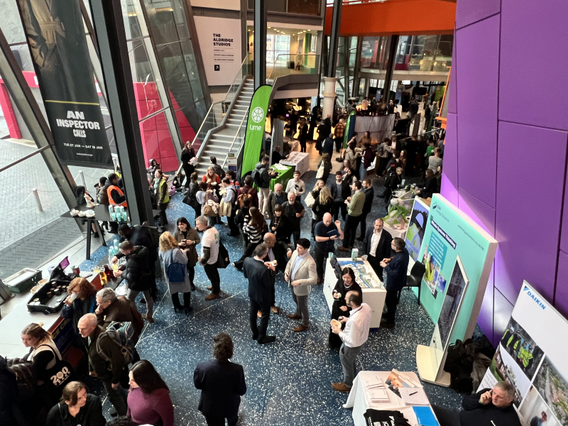 lots of people looking around exhibition stands in a large open hall