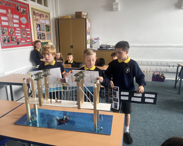 Primary school children holding up a model bridge.