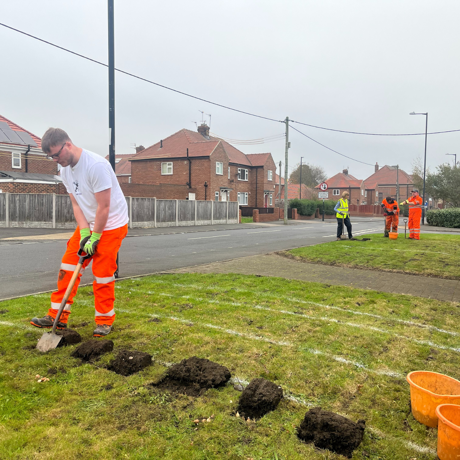 Boy in high vis digging a hole in a garden.